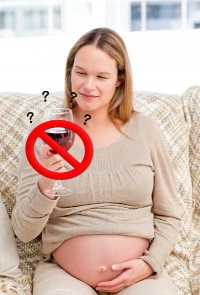 Pregnant woman looking at a glass of red wine