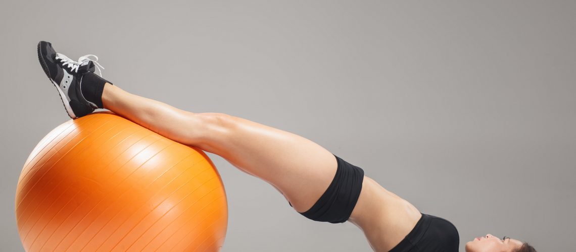 Young woman with a pilates ball doing pelvic floor exercise